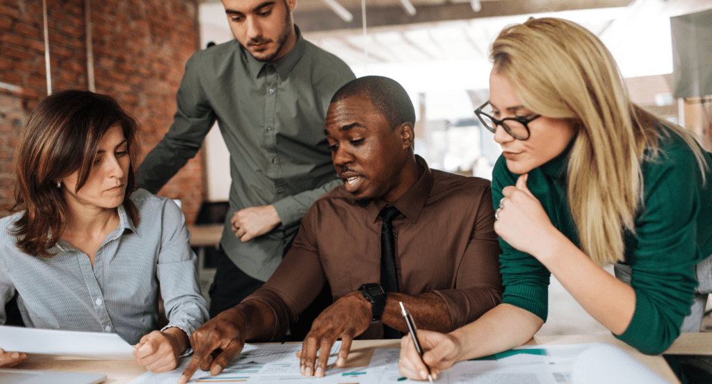 Young multi-cultural group of people sitting around a desk in an office workplace.